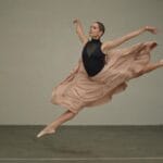 Balerina w skoku w powietrzu ćwiczy choreografię w sali tanecznej